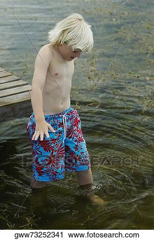 Stock Image - High angle view of a boy walking in water. Fotosearch