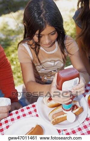 High angle view of a girl squeezing ketchup on a hot dog View Large Photo Image Stock Image - High angle view of a girl squeezing ketchup on a hot dog. Fotosearch