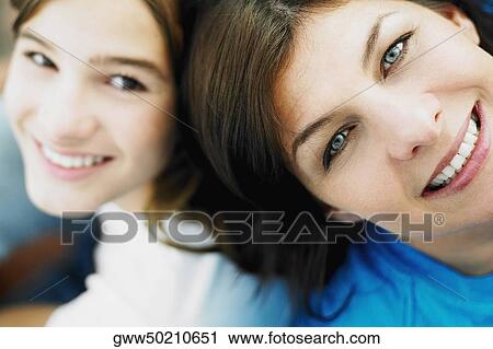 Stock Image - High angle view of a mature woman and her daughter sitting back to back. Fotosearch