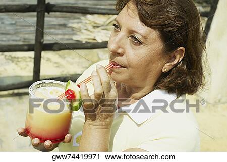 Stock Image - High angle view of a mature woman drinking juice. Fotosearch