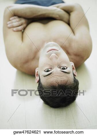 Stock Image - High angle view of a mid adult man lying on the floor. Fotosearch