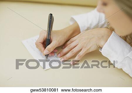 High angle view of a mid adult woman writing on a sheet of paper View Large Photo Image Stock Image - High angle view of a mid adult woman writing on a sheet of paper. Fotosearch
