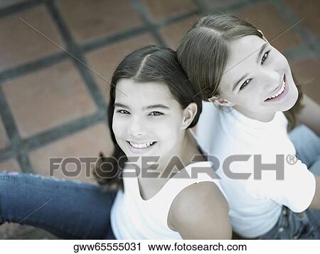 High angle view of a teenage girl and her sister sitting back to back View Large Photo Image Stock Image - High angle view of a teenage girl and her sister sitting back to back. Fotosearch