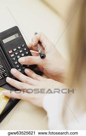 High angle view of a woman using a calculator and holding a pen View Large Photo Image Stock Image - High angle view of a woman using a calculator and holding a pen. Fotosearch