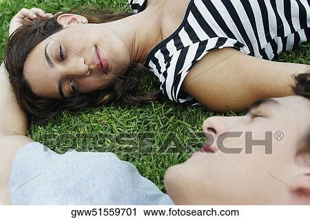 High angle view of a young couple lying on the grass in a park View Large Photo Image Stock Image - High angle view of a young couple lying on the grass in a park. Fotosearch