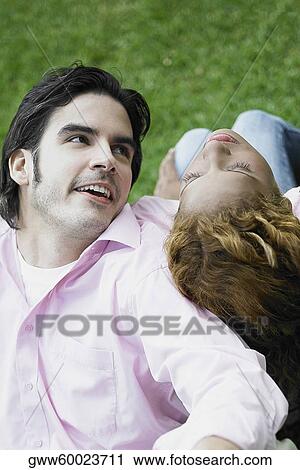 Stock Image - High angle view of a young couple sitting back to back. Fotosearch