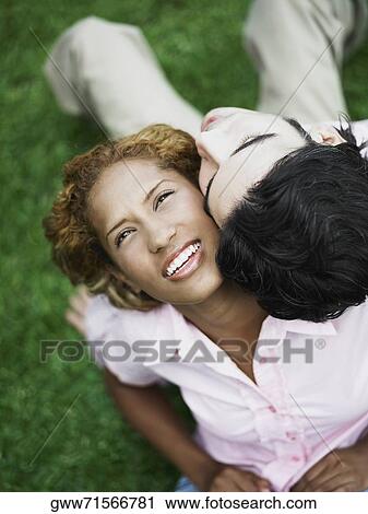 Stock Image - High angle view of a young couple sitting back to back. Fotosearch