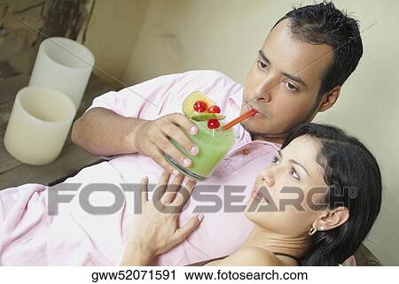 High angle view of a young man drinking juice with a young woman sitting beside him View Large Photo Image Stock Image - High angle view of a young man drinking juice with a young woman sitting beside him. Fotosearch