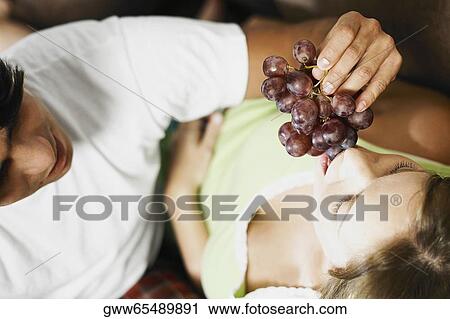 High angle view of a young man feeding a young woman red grapes View Large Photo Image Stock Image - High angle view of a young man feeding a young woman red grapes. Fotosearch