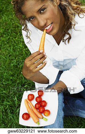 High angle view of a young woman eating a carrot View Large Photo Image Stock Image - High angle view of a young woman eating a carrot. Fotosearch