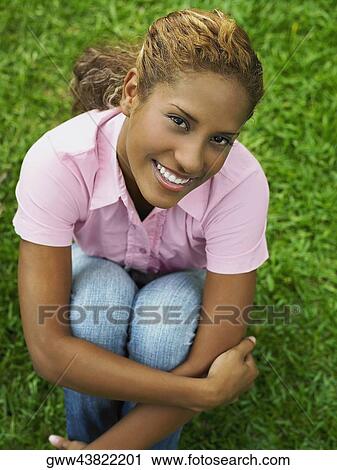 High angle view of a young woman hugging her knees View Large Photo Image Stock Image - High angle view of a young woman hugging her knees. Fotosearch