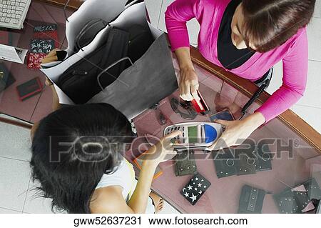 High angle view of a young woman feeding the amount in a credit card reader View Large Photo Image Stock Image - High angle view of a young woman feeding the amount in a credit card reader. Fotosearch