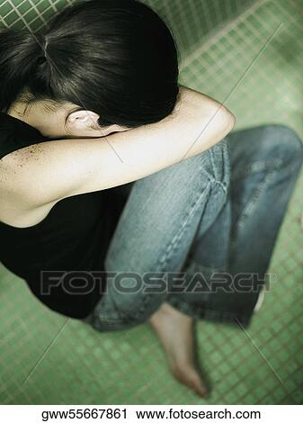 High angle view of a young woman sitting in the bathroom with her face down View Large Photo Image Stock Image - High angle view of a young woman sitting in the bathroom with her face down. Fotosearch