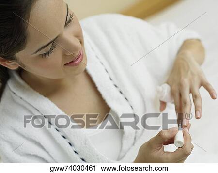 Stock Image - High angle view of a young woman polishing her nails. Fotosearch