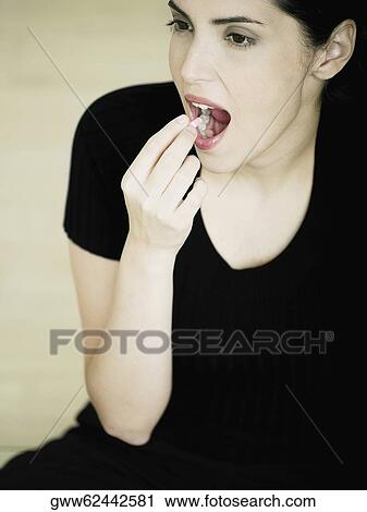 High angle view of a young woman taking a capsule View Large Photo Image Stock Image - High angle view of a young woman taking a capsule. Fotosearch