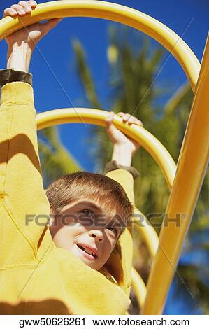 Low angle view of a boy hanging on a jungle gym View Large Photo Image Stock Image - Low angle view of a boy hanging on a jungle gym. Fotosearch