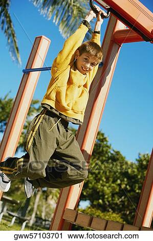 Low angle view of a boy hanging on a jungle gym View Large Photo Image Stock Image - Low angle view of a boy hanging on a jungle gym. Fotosearch
