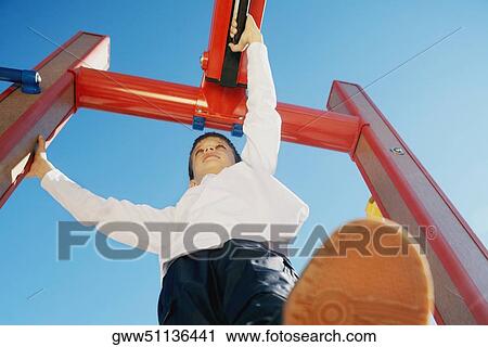 Low angle view of a boy on a jungle gym View Large Photo Image Stock Image - Low angle view of a boy on a jungle gym. Fotosearch