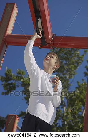 Stock Image - Low angle view of a boy playing on a jungle gym. Fotosearch