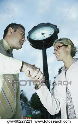 Stock Image - Low angle view of a businessman and a businesswoman shaking hands. Fotosearch