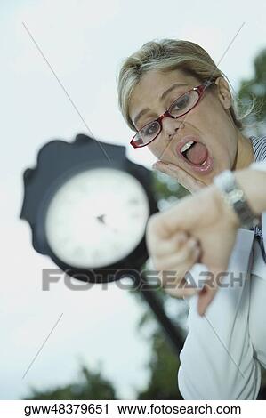 Low angle view of a businesswoman looking at a wristwatch View Large Photo Image Stock Image - Low angle view of a businesswoman looking at a wristwatch. Fotosearch
