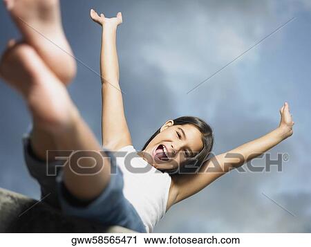 Stock Image - Low angle view of a girl shouting with her arm raised. Fotosearch