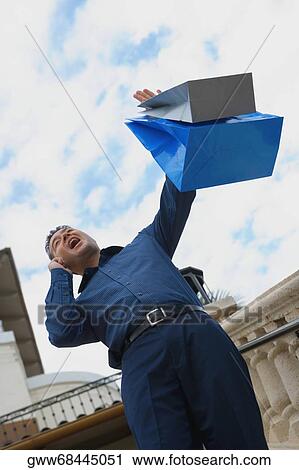 Stock Image - Low angle view of a mid adult man standing on steps with shopping bags. Fotosearch