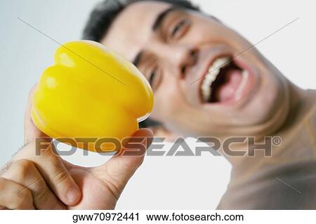 Low angle view of a mid adult man laughing and holding a yellow bell pepper View Large Photo Image Stock Image - Low angle view of a mid adult man laughing and holding a yellow bell pepper. Fotosearch