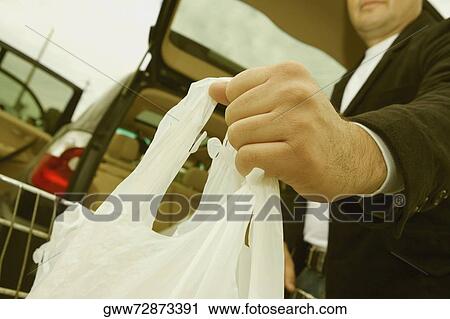 Stock Image - Low angle view of a mid adult man holding shopping bags. Fotosearch