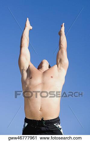 Stock Image - Low angle view of a mid adult man with his arms raised. Fotosearch