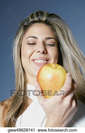 Low angle view of a mid adult woman holding an apple View Large Photo Image Stock Image - Low angle view of a mid adult woman holding an apple. Fotosearch
