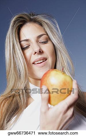 Stock Image - Low angle view of a mid adult woman holding an apple. Fotosearch