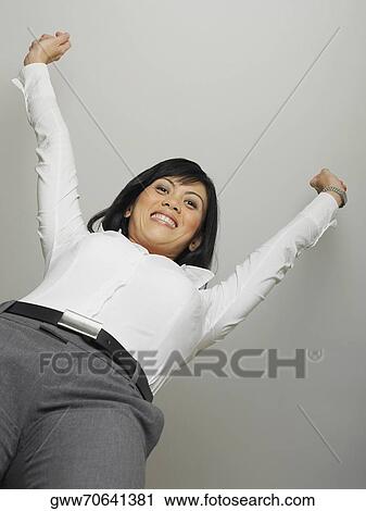 Low angle view of a mid adult woman standing with her arms raised View Large Photo Image Stock Image - Low angle view of a mid adult woman standing with her arms raised. Fotosearch