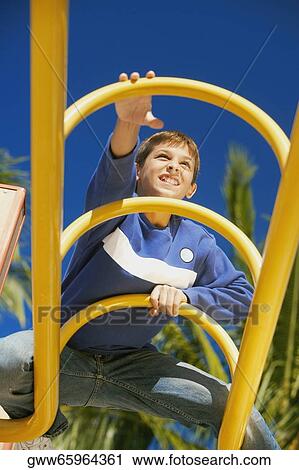Low angle view of a teenage boy on a jungle gym View Large Photo Image Stock Image - Low angle view of a teenage boy on a jungle gym. Fotosearch