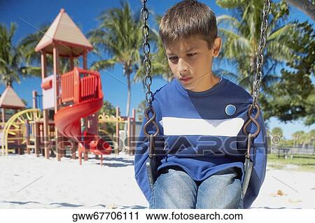 Low angle view of a teenage boy sitting on a swing and looking down View Large Photo Image Stock Image - Low angle view of a teenage boy sitting on a swing and looking down. Fotosearch