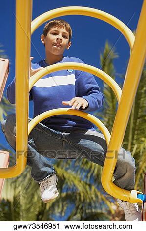 Low angle view of a teenage boy sitting on a jungle gym View Large Photo Image Stock Image - Low angle view of a teenage boy sitting on a jungle gym. Fotosearch