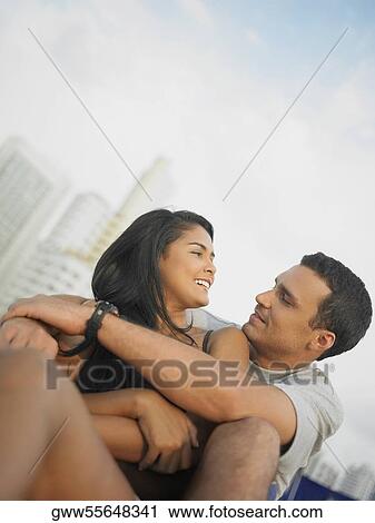 Low angle view of a young couple sitting and looking at each other View Large Photo Image Stock Image - Low angle view of a young couple sitting and looking at each other. Fotosearch