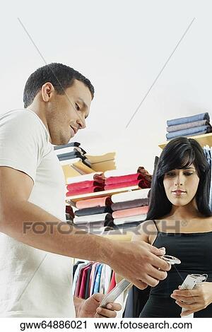 Stock Image - Low angle view of a young couple choosing a belt. Fotosearch