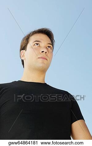 Low angle view of a young man looking away View Large Photo Image Stock Image - Low angle view of a young man looking away. Fotosearch