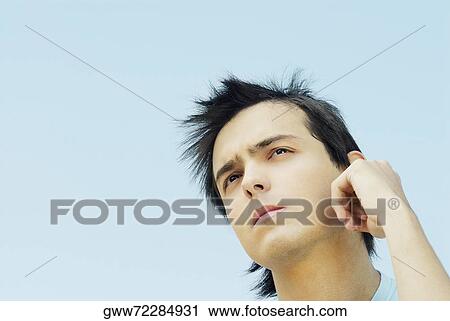 Low angle view of a young man thinking View Large Photo Image Stock Image - Low angle view of a young man thinking. Fotosearch