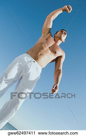 Low angle view of a young man with his hand raised View Large Photo Image Stock Image - Low angle view of a young man with his hand raised. Fotosearch