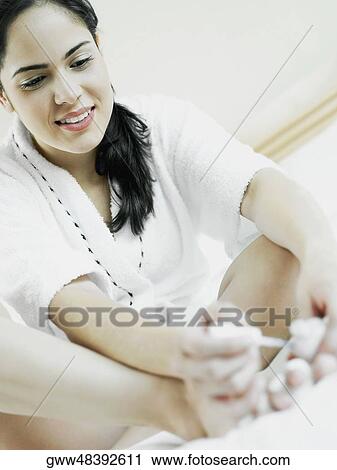 Low angle view of a young woman sitting and polishing her nail with nail polish View Large Photo Image Stock Image - Low angle view of a young woman sitting and polishing her nail with nail polish. Fotosearch