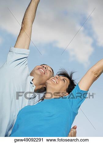 Low angle view of mature couple with their arms raised View Large Photo Image Stock Image - Low angle view of mature couple with their arms raised. Fotosearch