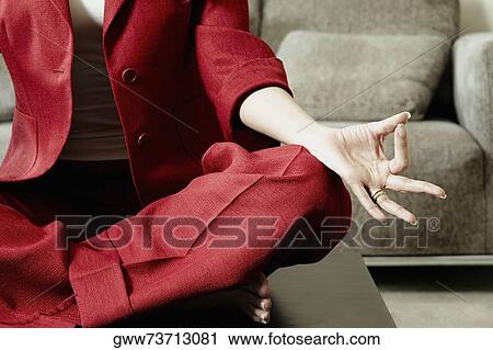 Stock Image - Low section view of a businesswoman meditating. Fotosearch