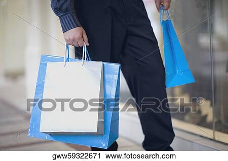 Low section view of a man carrying shopping bags View Large Photo Image Stock Image - Low section view of a man carrying shopping bags. Fotosearch