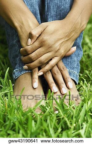 Low section view of a woman sitting on the grass with hugging her knees View Large Photo Image Stock Image - Low section view of a woman sitting on the grass with hugging her knees. Fotosearch