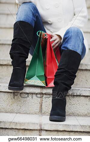 Low section view of a woman sitting on steps with shopping bags View Large Photo Image Stock Image - Low section view of a woman sitting on steps with shopping bags. Fotosearch