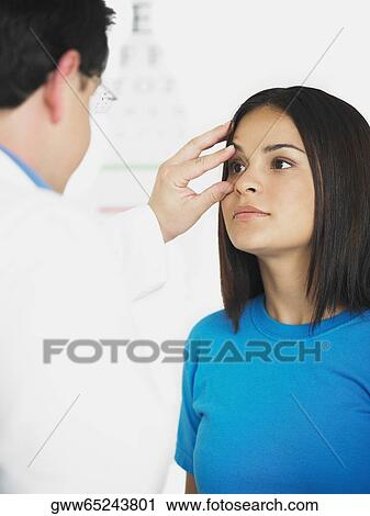 Stock Image - Male doctor examining a female patient. Fotosearch