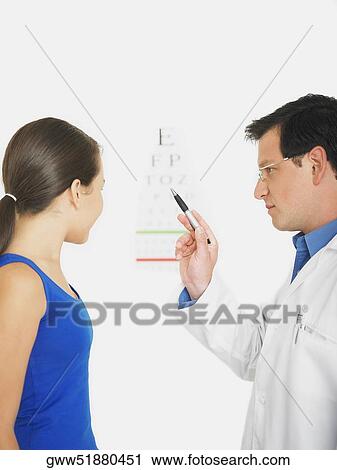 Stock Image - Male doctor showing the eye chart to a female patient. Fotosearch