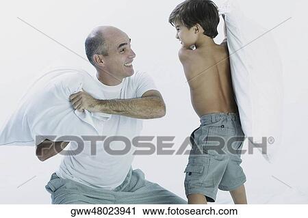 Stock Image - Mature man and his son having a pillow fight. Fotosearch